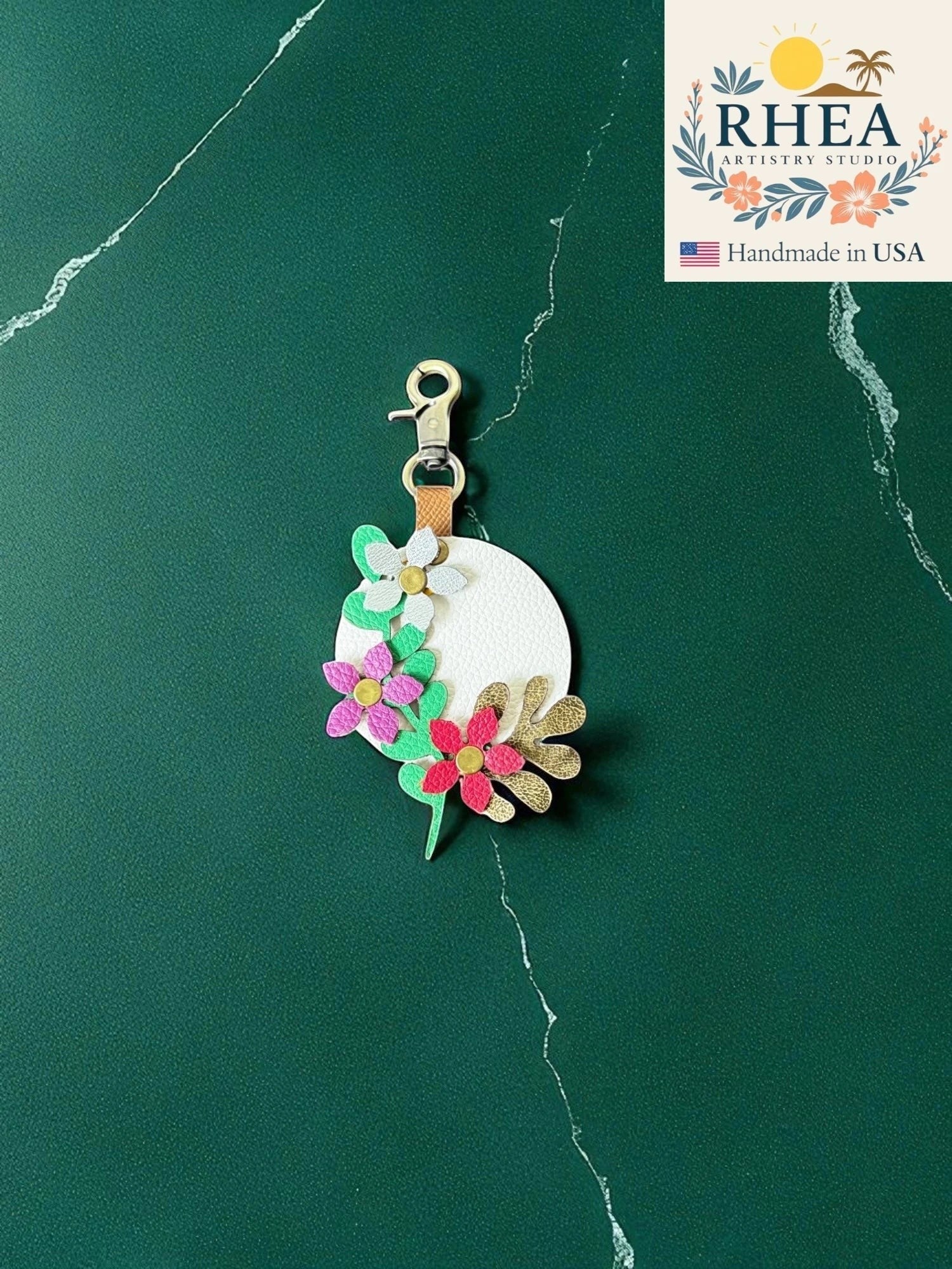 Rhea Artistry Studio white leather charm with layered floral and leaf appliques in pink, red, gold, and green.