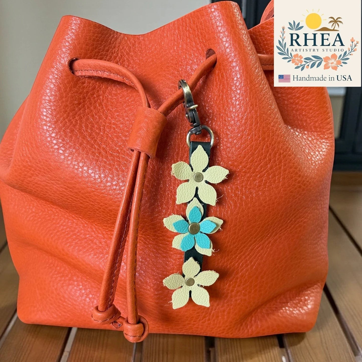 Rhea Artistry Studio handmade leather floral charm with brushed brass clasp, featuring cream and teal flowers.