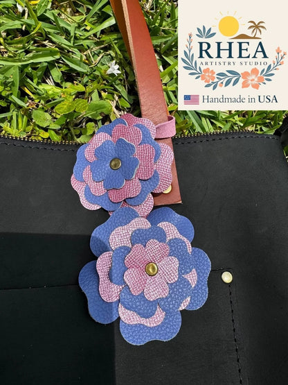 Rhea Artistry Studio double leather flower charm in Blue Bell and Barbie Pink, handcrafted from full-grain leather with brass rivets.