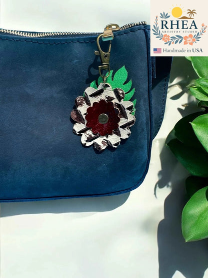 Rhea Artistry Studio leather monstera leaf and flower charm with brass clasp on navy blue purse.