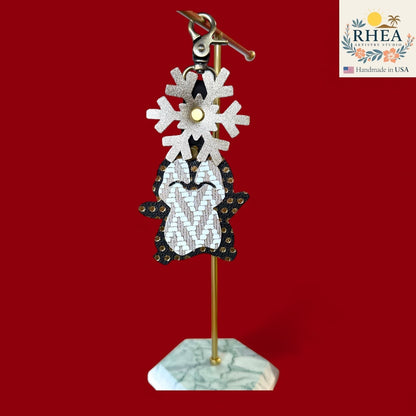 Rhea Artistry Studio handmade leather penguin charm with snowflake detail and gold accents, perfect for winter bags.