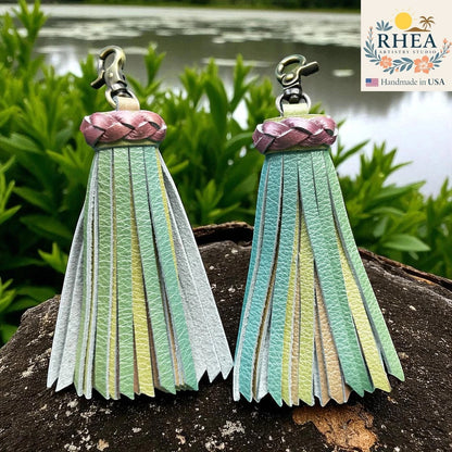 Rhea Artistry Studio handmade leather tassel keychain in pastel green, yellow, and grey with a braided pink top and antique brass clasp.