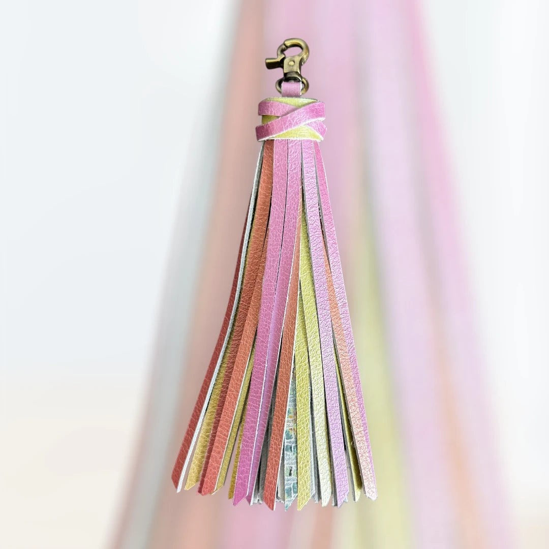 Rhea Artistry Studio handmade large leather tassel keychain in pastel pink, yellow, and orange with glitter finish and antique brass lobster clasp.