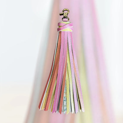 Rhea Artistry Studio handmade large leather tassel keychain in pastel pink, yellow, and orange with glitter finish and antique brass lobster clasp.