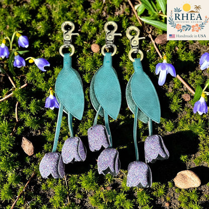 Rhea Artistry Studio teal leather tulip charm with purple glitter accents and gold lobster clasp, handmade in USA.