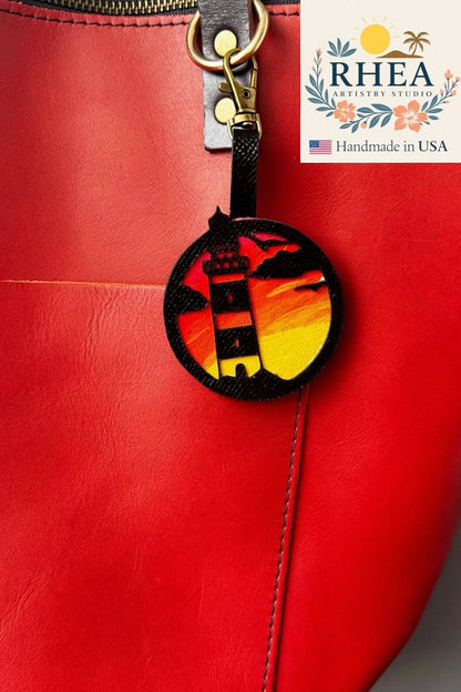 Rhea Artistry Studio hand-painted leather lighthouse charm with coastal sunset scene on vegetable-tanned leather.