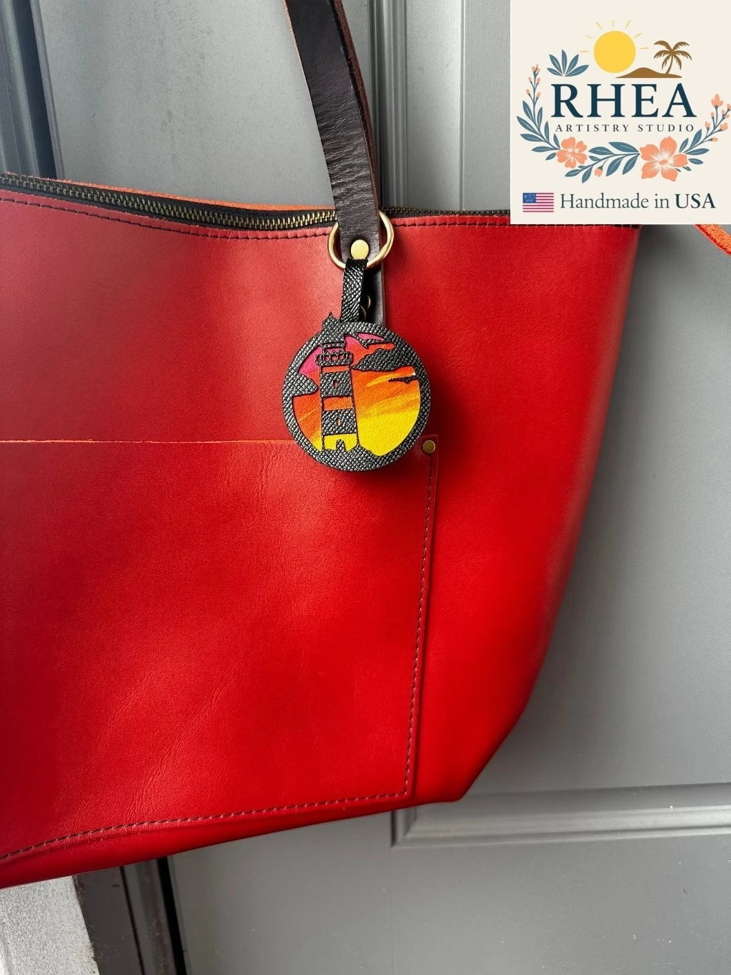 Rhea Artistry Studio hand-painted leather lighthouse charm with coastal sunset scene on vegetable-tanned leather.