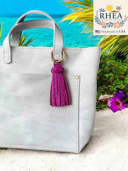 Rhea Artistry Studio handmade chunky magenta leather tassel bag charm with gold lobster clasp.