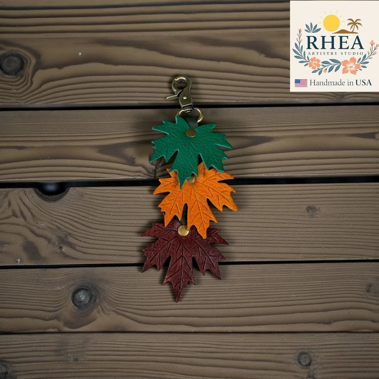 Rhea Artistry Studio layered maple leaf leather bag charm in green, orange, and burgundy with vein detail and brass hardware.