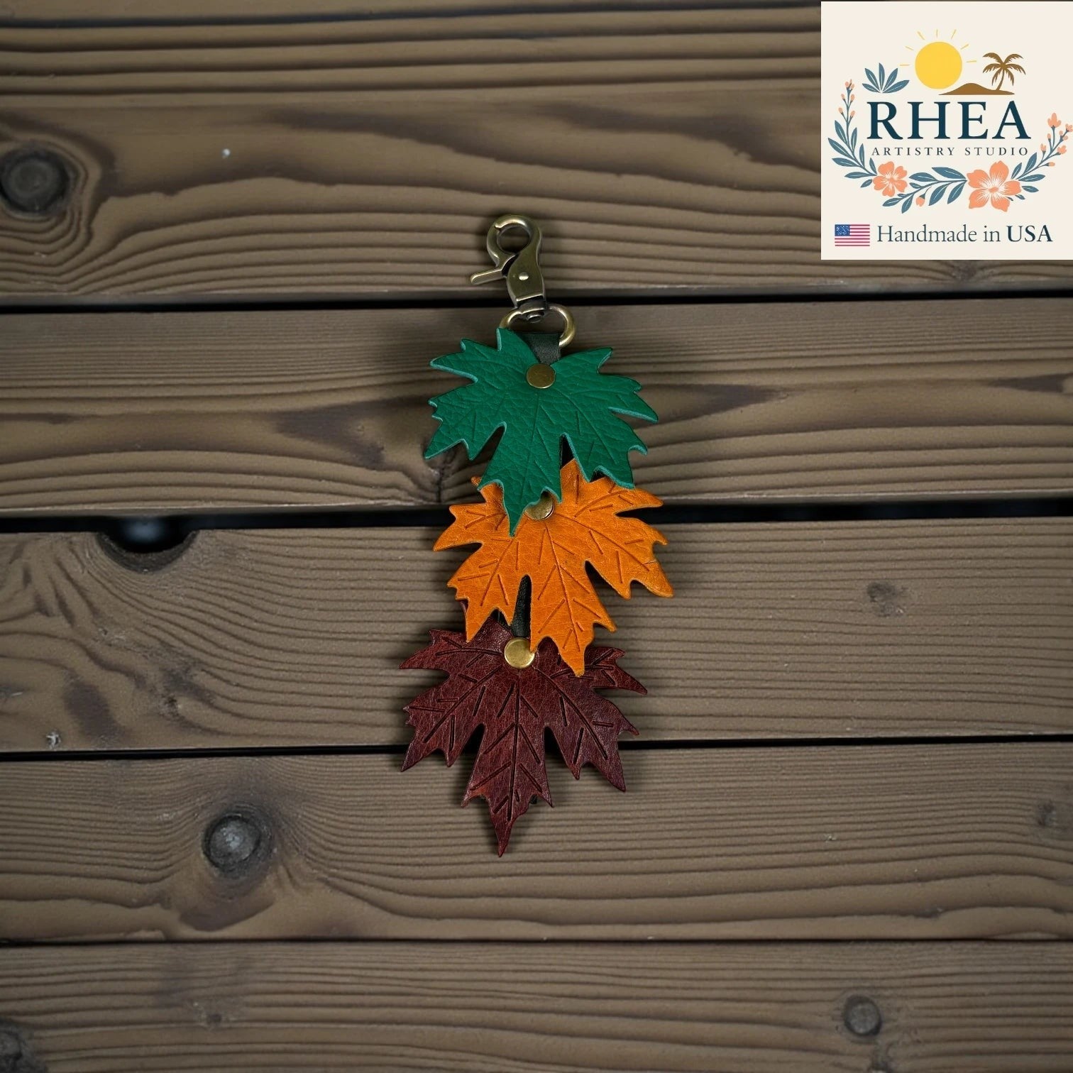 Rhea Artistry Studio layered maple leaf leather bag charm in green, orange, and burgundy with vein detail and brass hardware.