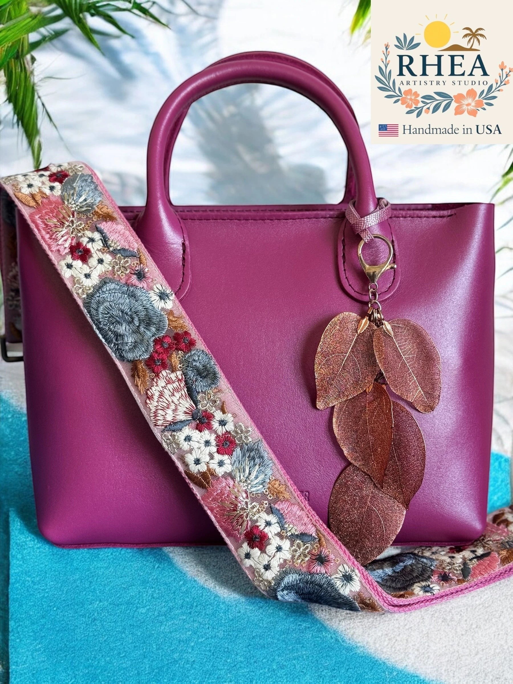 Rhea Artistry Studio handmade metallic copper leaf bag charm with embroidered floral strap on a magenta handbag.