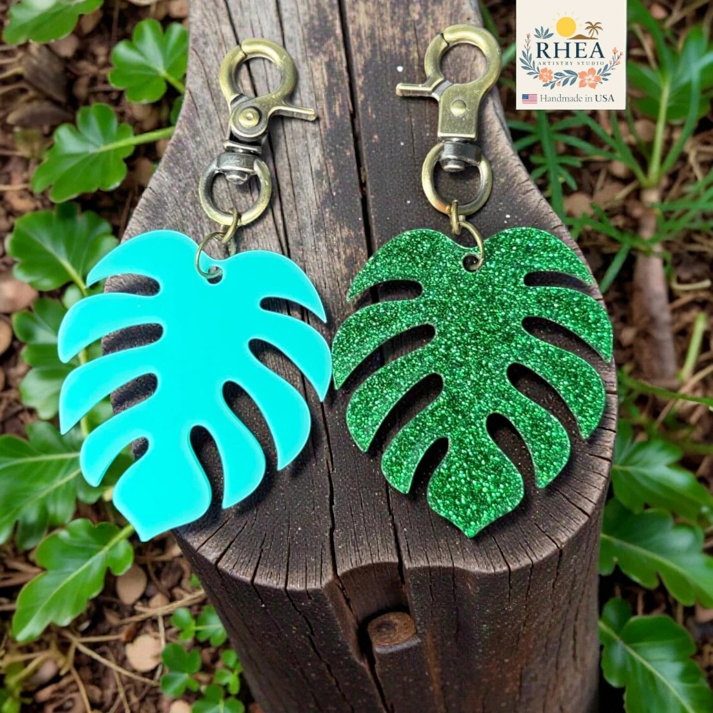 Rhea Artistry Studio teal and green glitter monstera leaf acrylic charms with antique brass clasps.