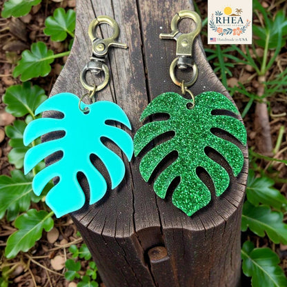 Rhea Artistry Studio teal and green glitter monstera leaf acrylic charms with antique brass clasps.