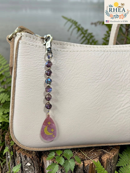 Rhea Artistry Studio moon and stars pendant bag charm with purple Czech glass beads and brass hardware.