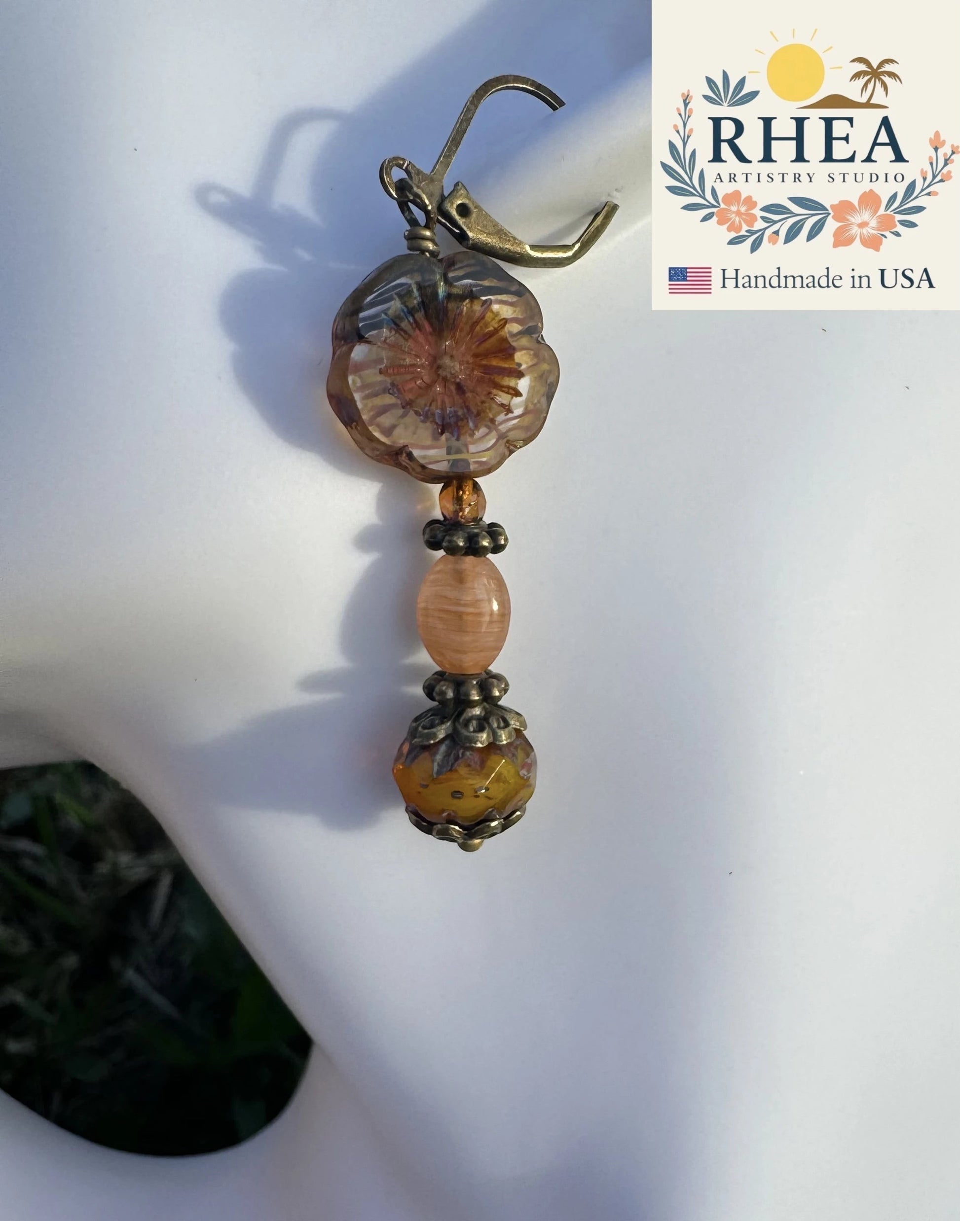 Rhea Artistry Studio mustard floral hibiscus drop earrings with brass accents, approx. 1.5-2 inches long.