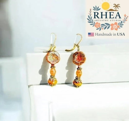 Rhea Artistry Studio mustard hibiscus drop earrings with brass accents, approx. 1.5-2 inches long, handcrafted in USA.