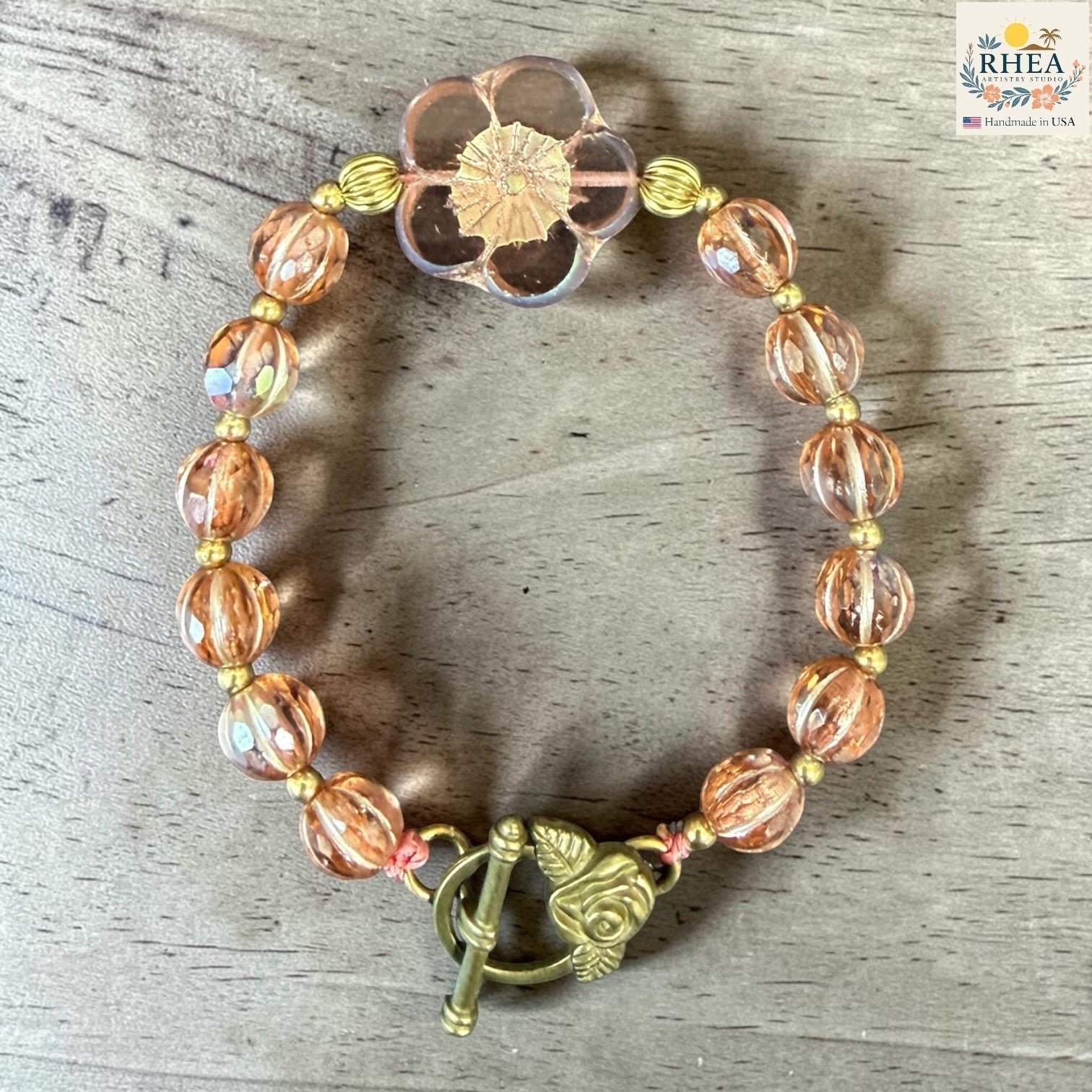 Rhea Artistry Studio peach and gold glass bead bracelet with floral focal bead and rose toggle clasp.