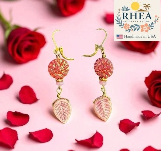 Rhea Artistry Studio pink dahlia floral drop earrings with leafy accents and brass hardware, approx. 2 inches long.