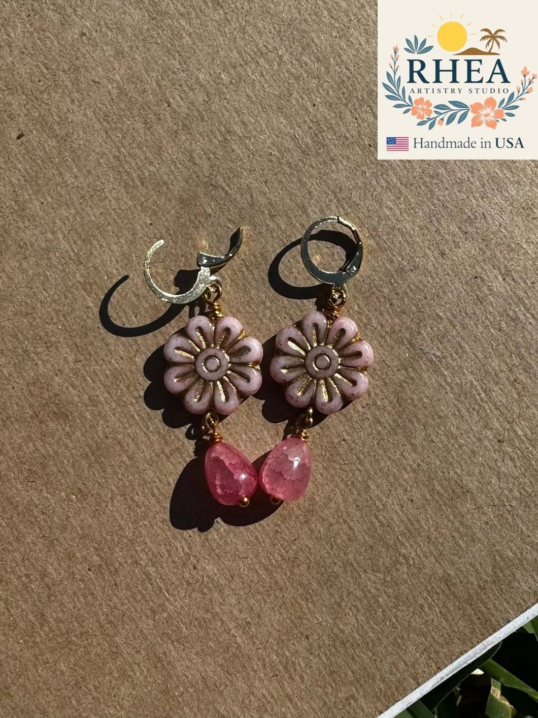 Rhea Artistry Studio pale pink daisy flower earrings with gold wash detail and pink gemstone drops.