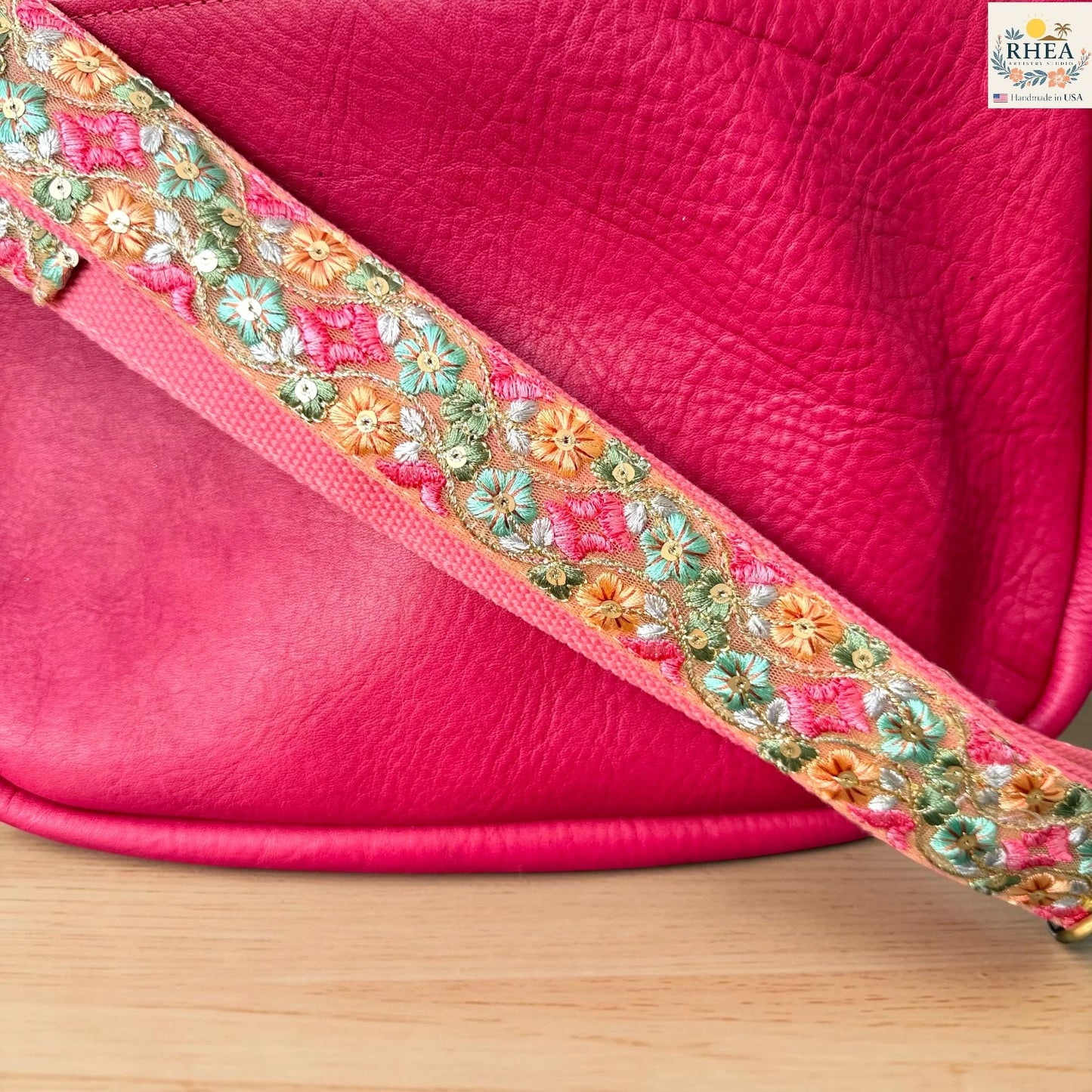 Rhea Artistry Studio blush pink crossbody strap with green, orange, and pink diamond floral embroidery, 2-inch width, adjustable length, close-up of embroidery detail.