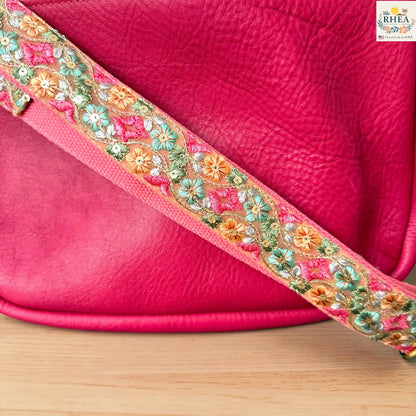 Rhea Artistry Studio blush pink crossbody strap with green, orange, and pink diamond floral embroidery, 2-inch width, adjustable length, close-up of embroidery detail.