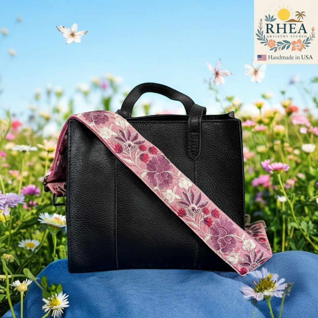 Rhea Artistry Studio pink crossbody strap with purple floral embroidery, 2-inch width, adjustable length, and brushed brass hardware.