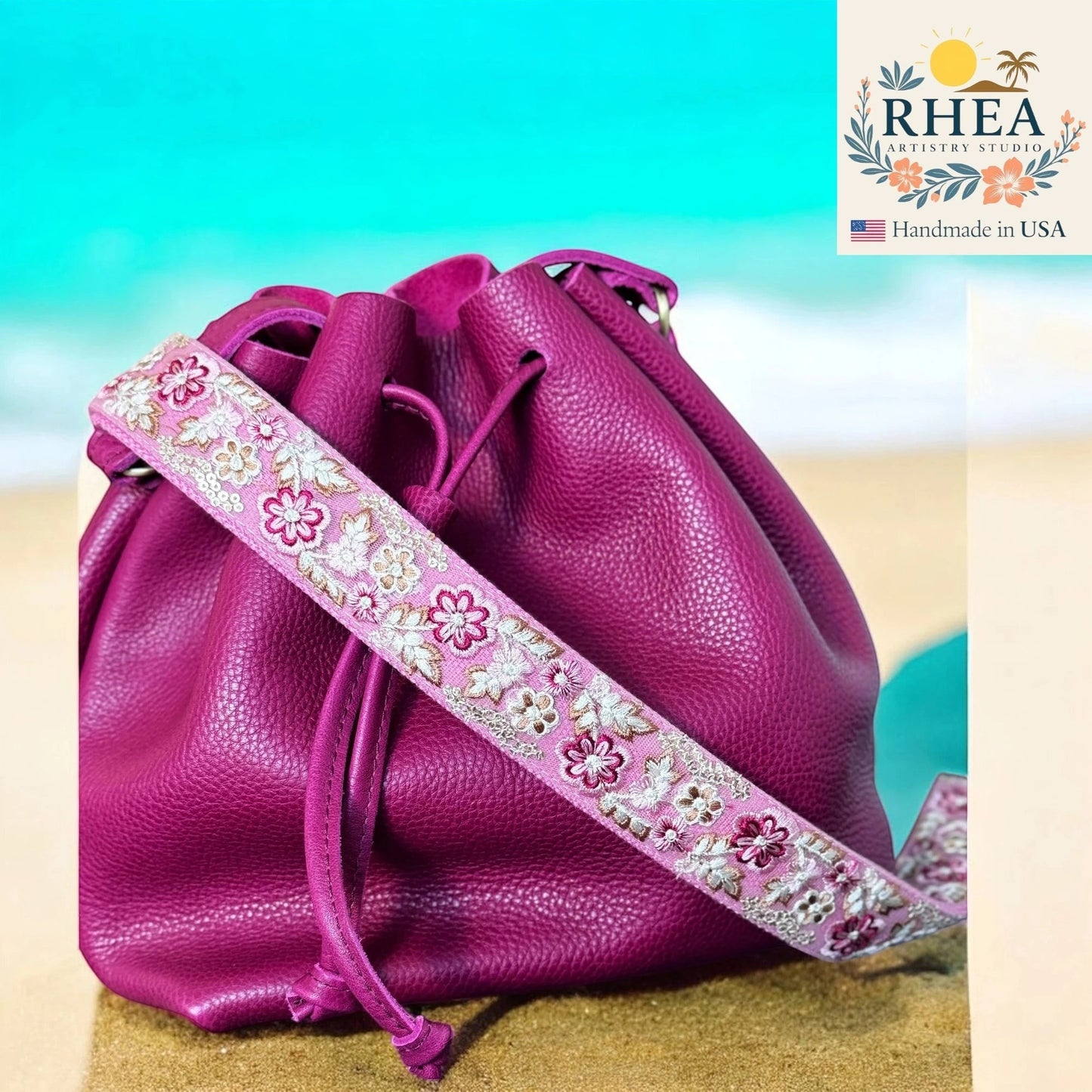 Rhea Artistry Studio pink embroidered lace crossbody strap with floral pattern on a magenta leather bucket bag.