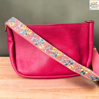 Rhea Artistry Studio blush pink crossbody strap with yellow floral and turquoise leaf embroidery, 1.5-inch width, adjustable length.