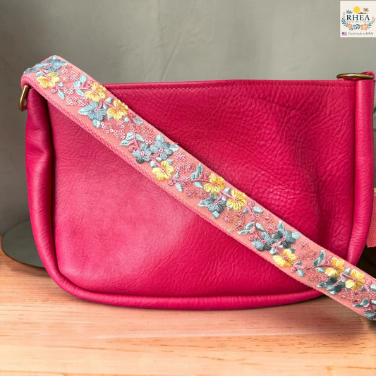 Rhea Artistry Studio blush pink crossbody strap with yellow floral and turquoise leaf embroidery, 1.5-inch width, adjustable length.
