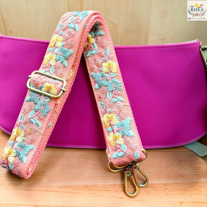 Rhea Artistry Studio blush pink crossbody strap with yellow floral and turquoise leaf embroidery, 1.5-inch width, adjustable length.