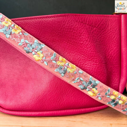  Rhea Artistry Studio coral pink crossbody strap with yellow floral and turquoise leaf embroidery, 1.5-inch width, adjustable length.