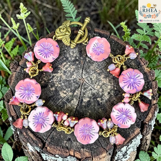 Rhea Artistry Studio handmade pink glass flower bead bracelet with purple centers and antique brass toggle clasp.