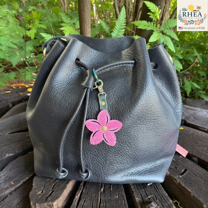 Rhea Artistry Studio pink glitter leather plumeria flower bag charm with brushed brass hardware.