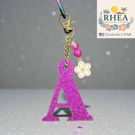 Rhea Artistry Studio glittery pink letter A charm with pink beads and a flower charm, attached to a keychain clasp.