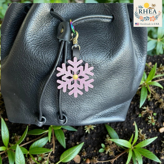 Rhea Artistry Studio pink glitter snowflake leather bag charm with rainbow clasp.