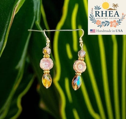 Rhea Artistry Studio pink glass hibiscus flower earrings with gold-filled findings and faceted amber drops.