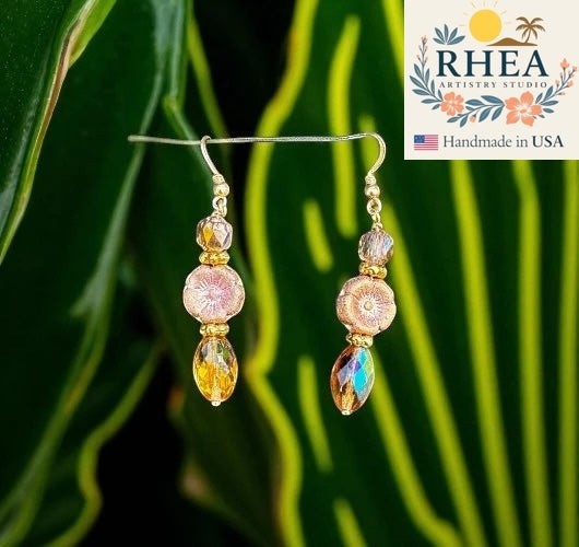 Rhea Artistry Studio pink glass hibiscus flower earrings with gold-filled findings and faceted amber drops.