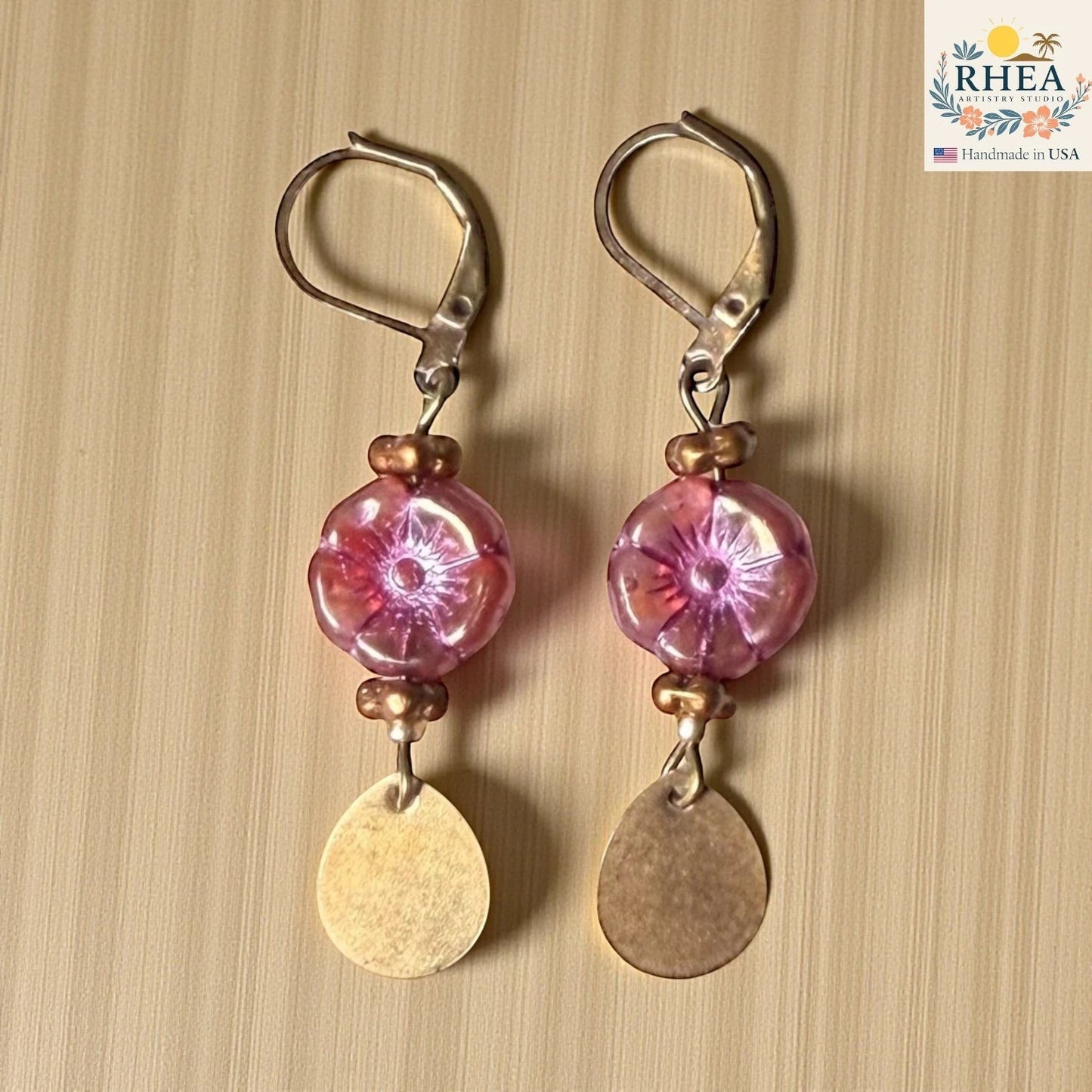 Rhea Artistry Studio pink hibiscus glass flower drop earrings with brass teardrop charms and leverback hooks.