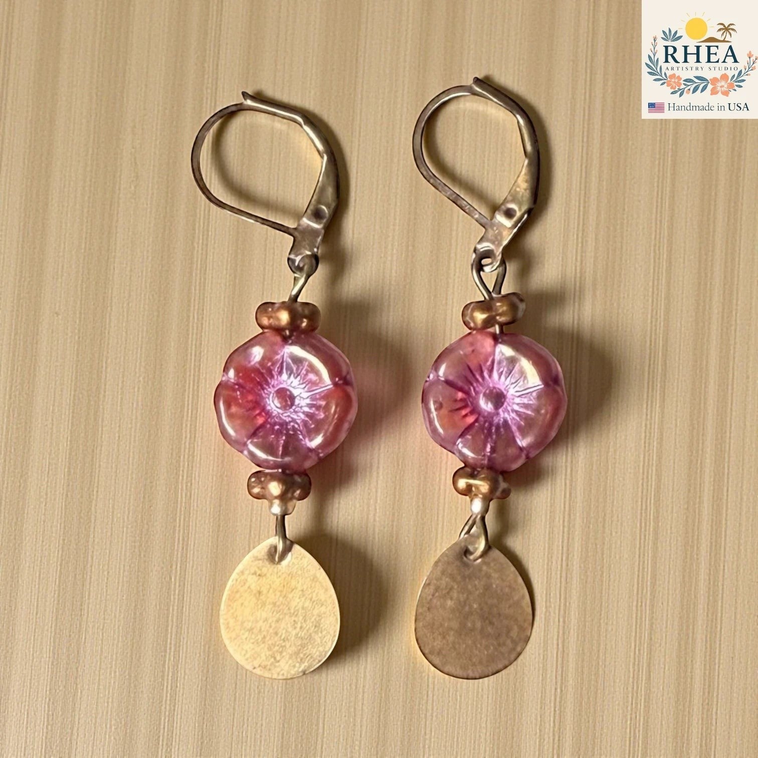 Rhea Artistry Studio pink hibiscus glass flower drop earrings with brass teardrop charms and leverback hooks.