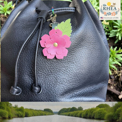Rhea Artistry Studio pink layered leather rose charm with green engraved leaf detail on black leather bag.