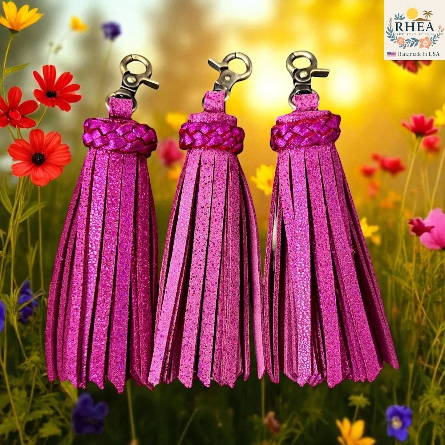 Rhea Artistry Studio handmade pink metallic leather tassel keychain with lobster clasp, set against a floral background.