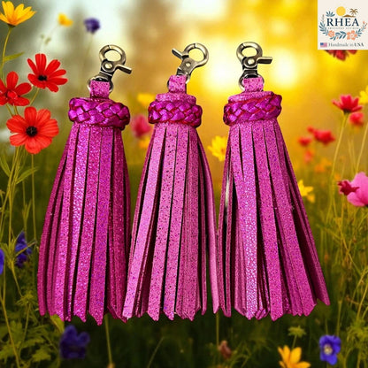Rhea Artistry Studio handmade pink metallic leather tassel keychain with lobster clasp, set against a floral background.