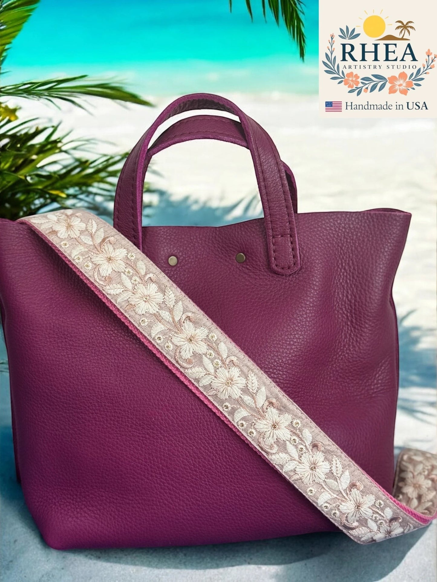 Rhea Artistry Studio plum flower embroidered crossbody strap with adjustable length and brushed brass hardware.