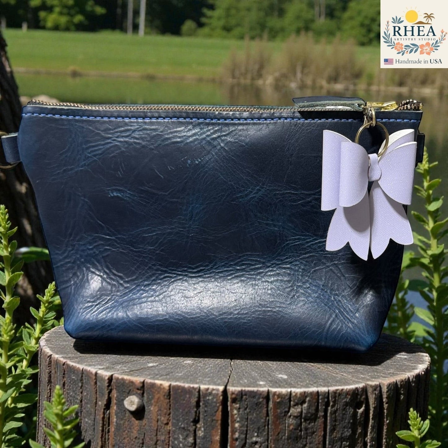 Rhea Artistry Studio handmade double-layer French bow charm in light purple with brass hardware, attached to a navy blue leather bag.