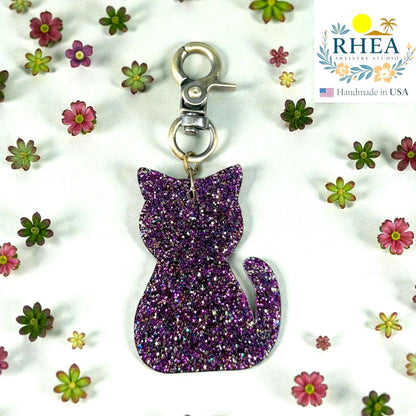 Rhea Artistry Studio purple glitter cat silhouette acrylic charm with antique brass clasp, perfect for bags or keys.