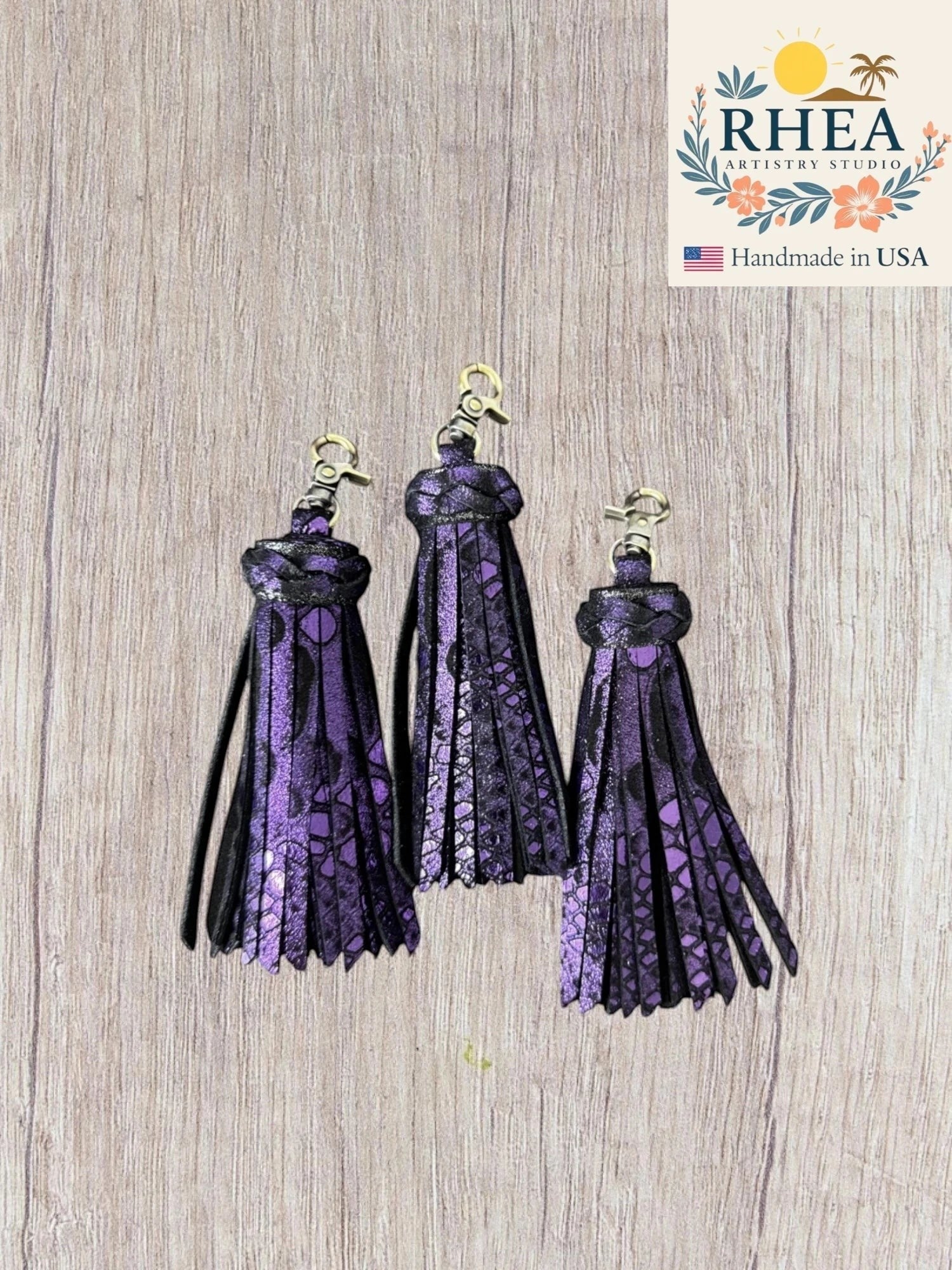 Rhea Artistry Studio handmade purple and black leather tassel keychain with lobster clasp. Chunky, layered design with metallic finish.