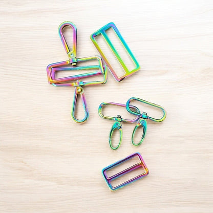 Rhea Artistry Studio rainbow iridescent hardware set including swivel clasps, strap adjusters, and D-rings for bag making.