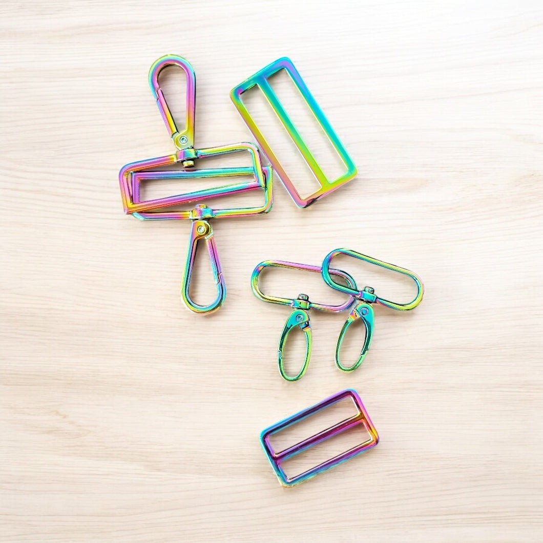 Rhea Artistry Studio rainbow iridescent metal hardware set including swivel clasps and strap adjusters for bags and straps.