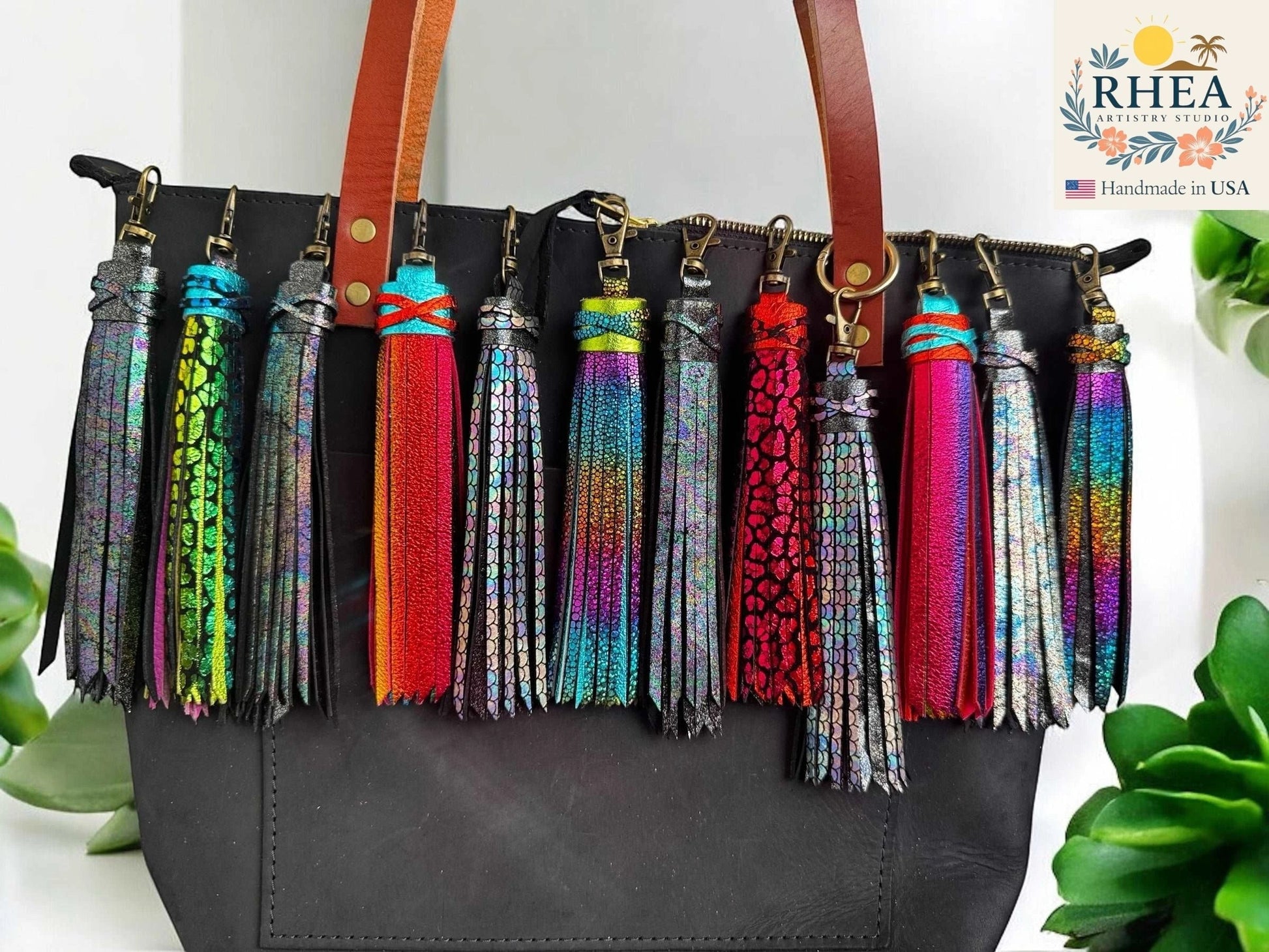 Rhea Artistry Studio handmade 7-inch rainbow chameleon leather tassel keychain with lobster clasp, attached to a black tote bag.
