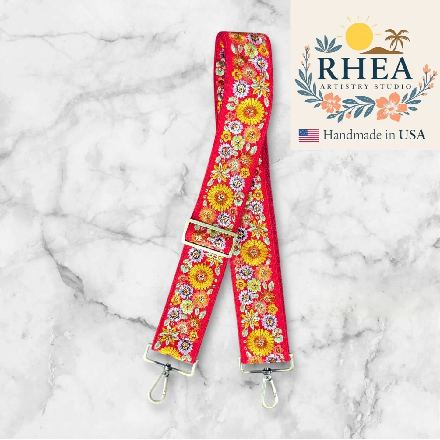 Rhea Artistry Studio red 2-inch wide strap with embroidered yellow, pink, and white flowers. Adjustable crossbody bag strap with brushed brass hardware.